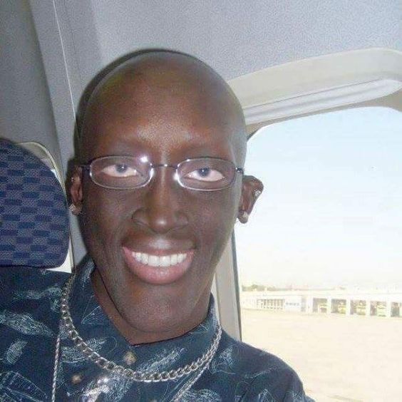 black guy with glasses in plane with white teeth smiling